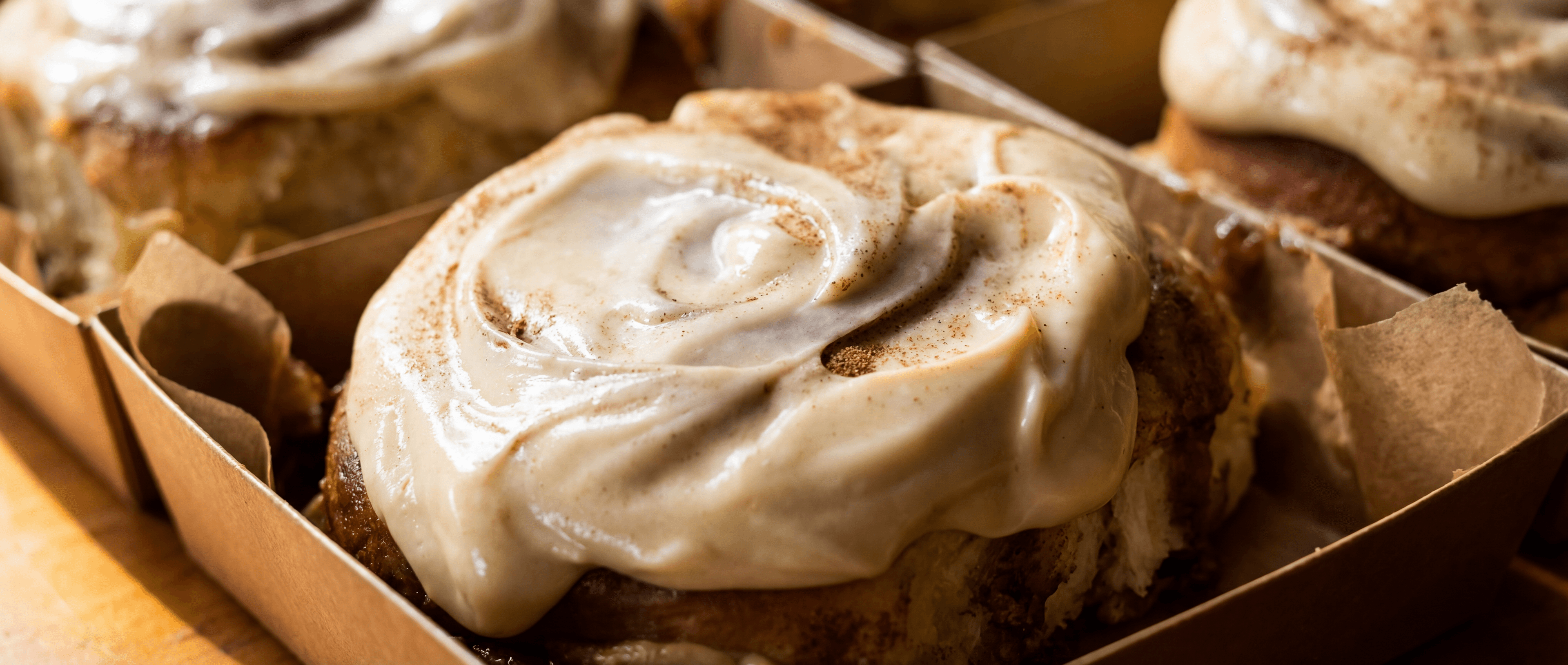 Close-up of a glazed cinnamon roll with soft pillowy interior exposed on a ceramic plate